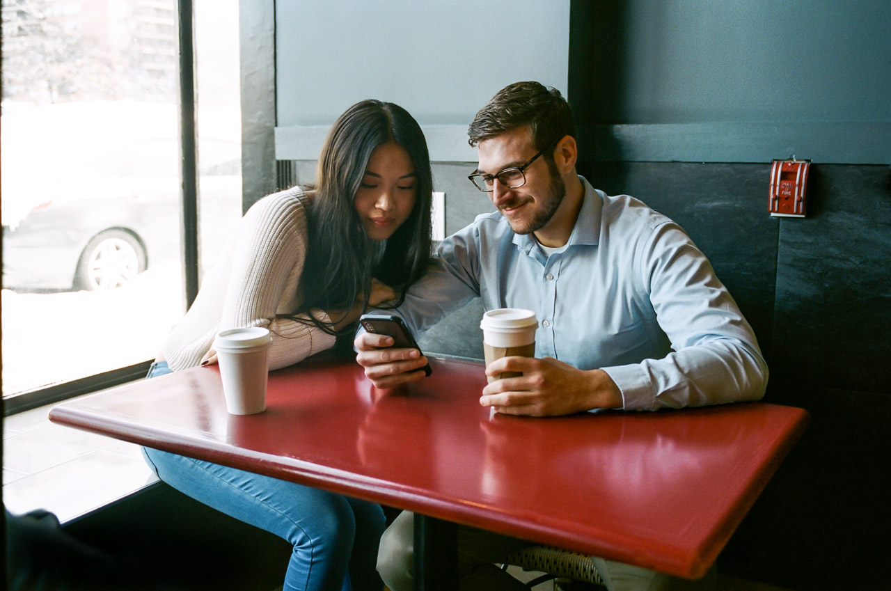 Man and woman in coffeeshop looking at mobile phone