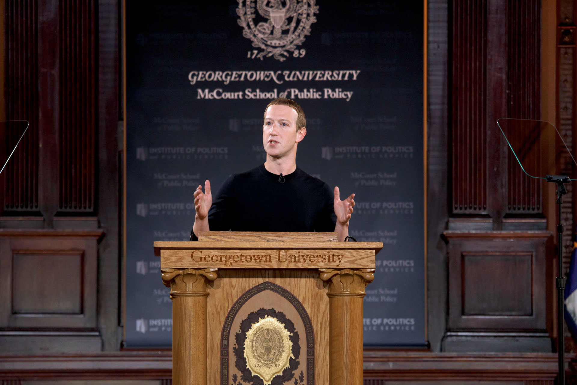 Mark Zuckerberg in black shirt onstage behind podium delivering speech