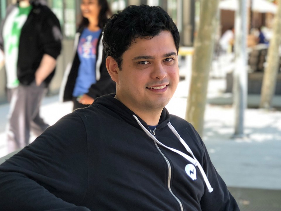 male employee Alberto B seated and smiling outdoors