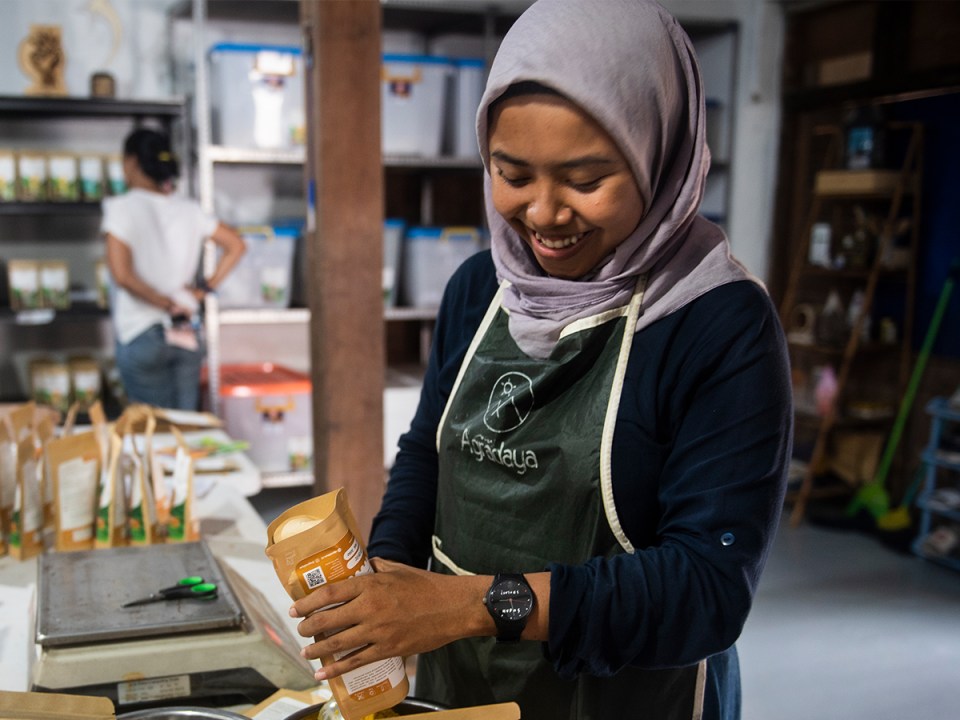smiling woman in headscarf and apron packaging spices