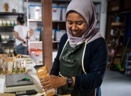 smiling woman in headscarf and apron packaging spices