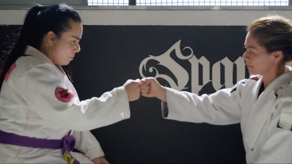 Photo of women on Jiu Jitsu mat giving each other a fist bump