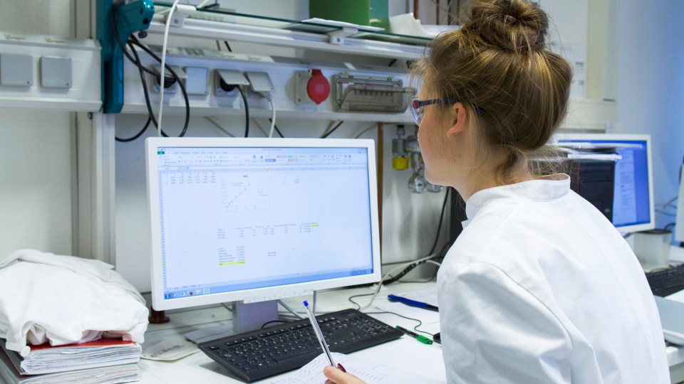 Laboratory technician with record working at computer