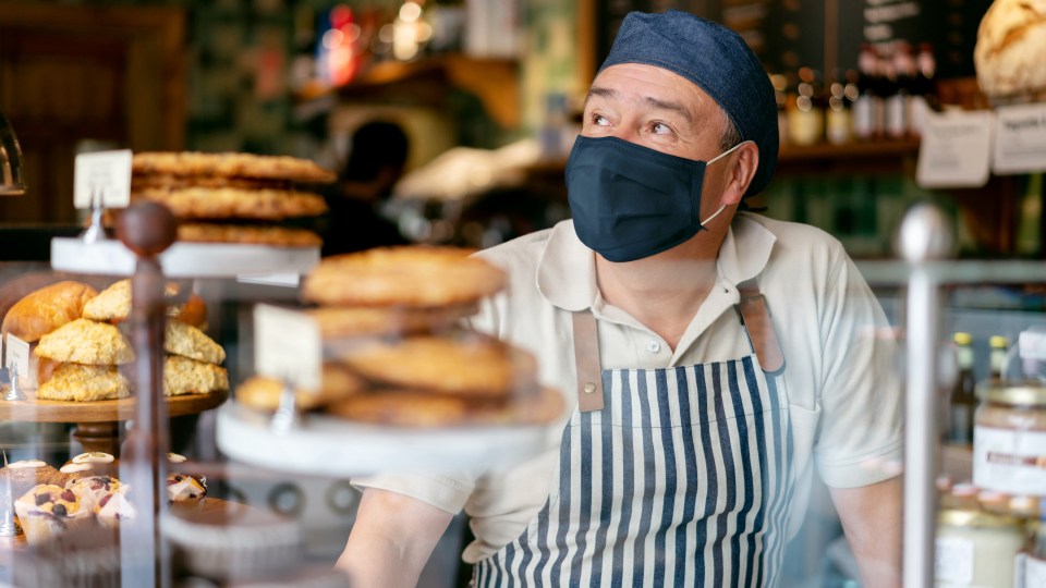 Man in mask working behind bakery counter