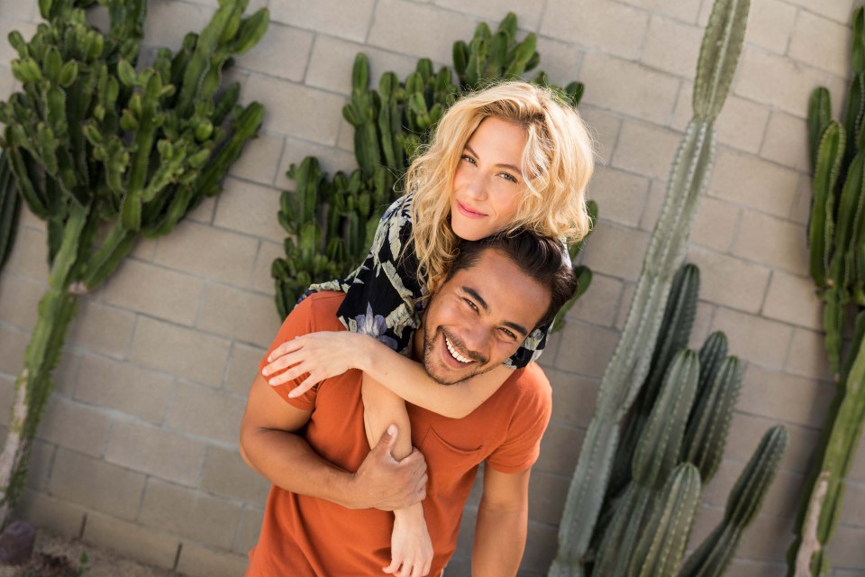 A couple posing in front of cactus.