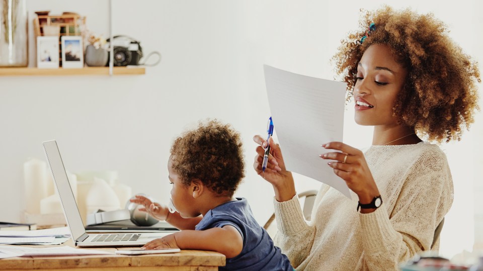 Woman working with her laptop, with a child in her lap.