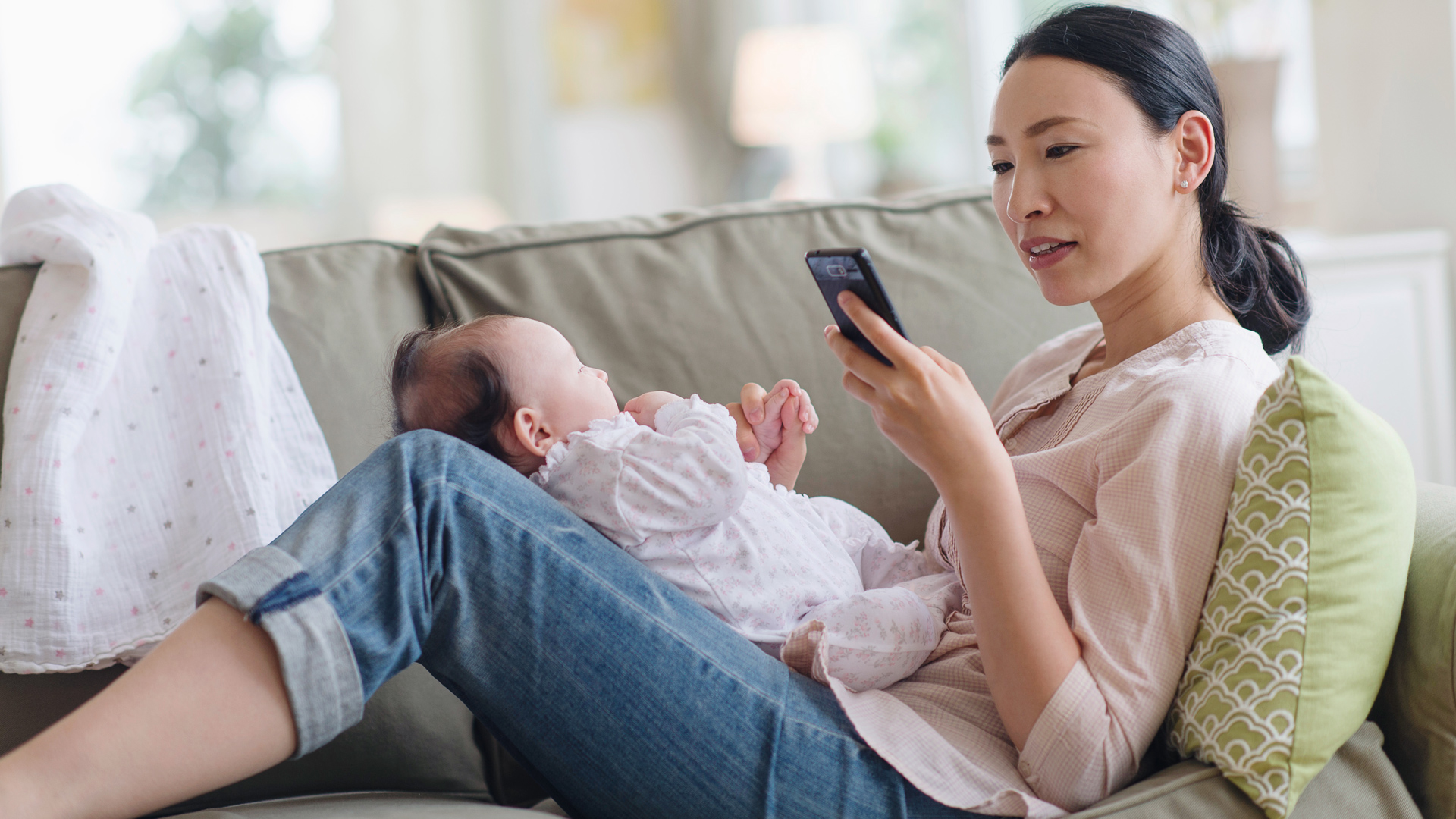 Mom holding baby and using smartphone