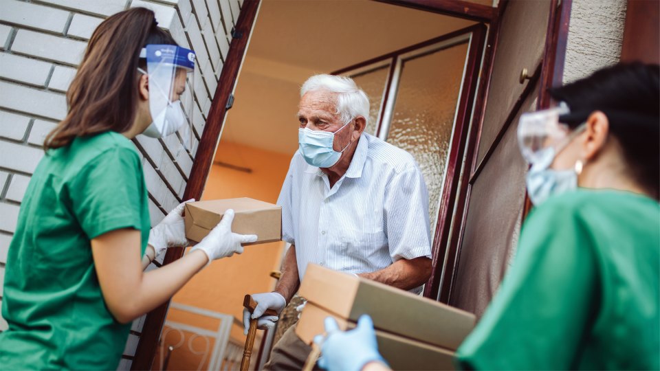 Photo of volunteers delivering a package to an elderly man