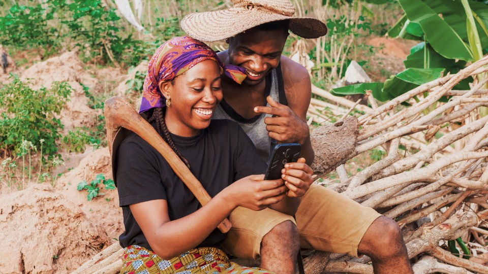 Photo of two people in a rural area looking at a phone