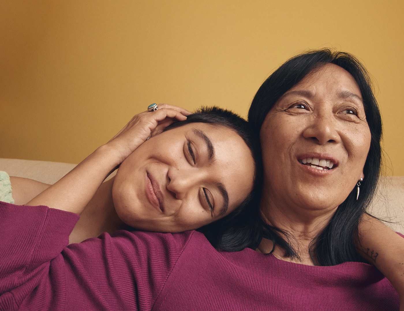 Photo of a woman leaning her head on another woman's shoulder, both smiling