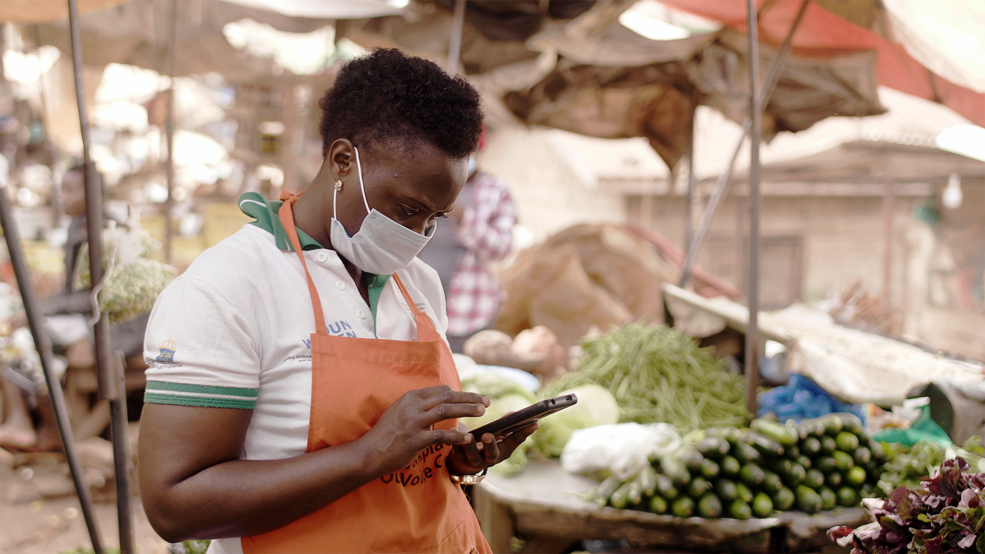 A person in a mask looking at their phone in a marketplace