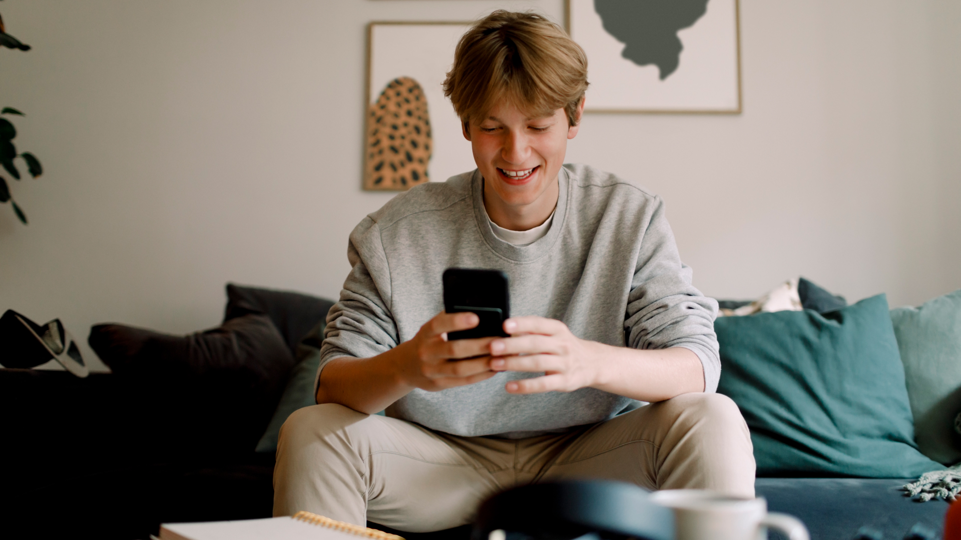 Photo of a teenage boy looking at his phone and smiling
