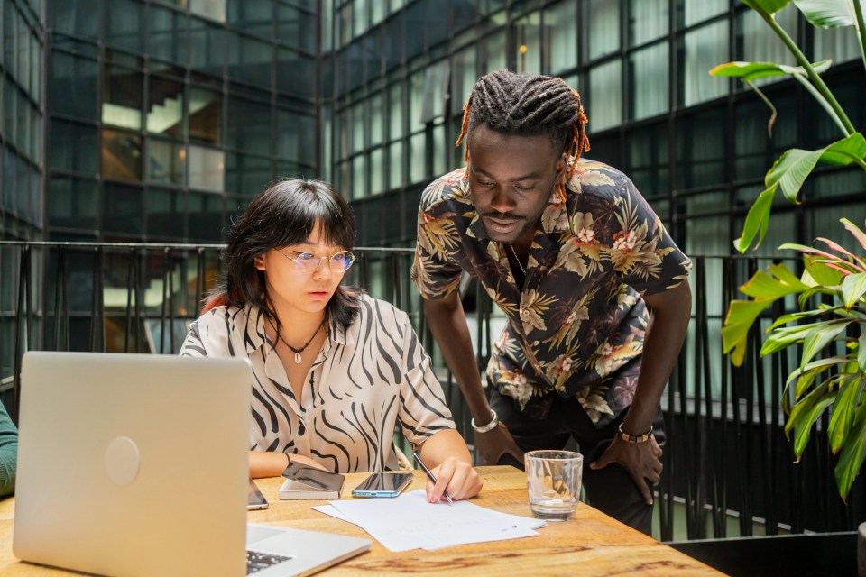 Two people working together at a desk in an office.