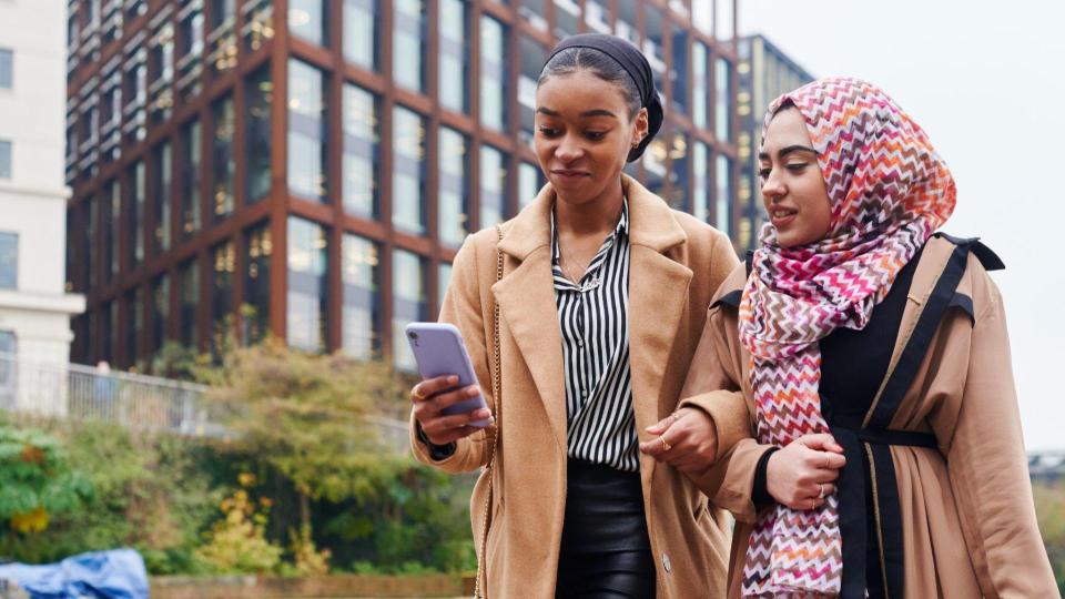 Two people walking looking at a mobile phone