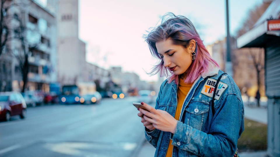 Young person using their mobile phone on a street