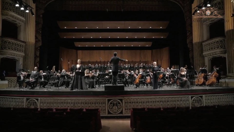 Stage with conductor, full orchestra and singers, in a concert hall
