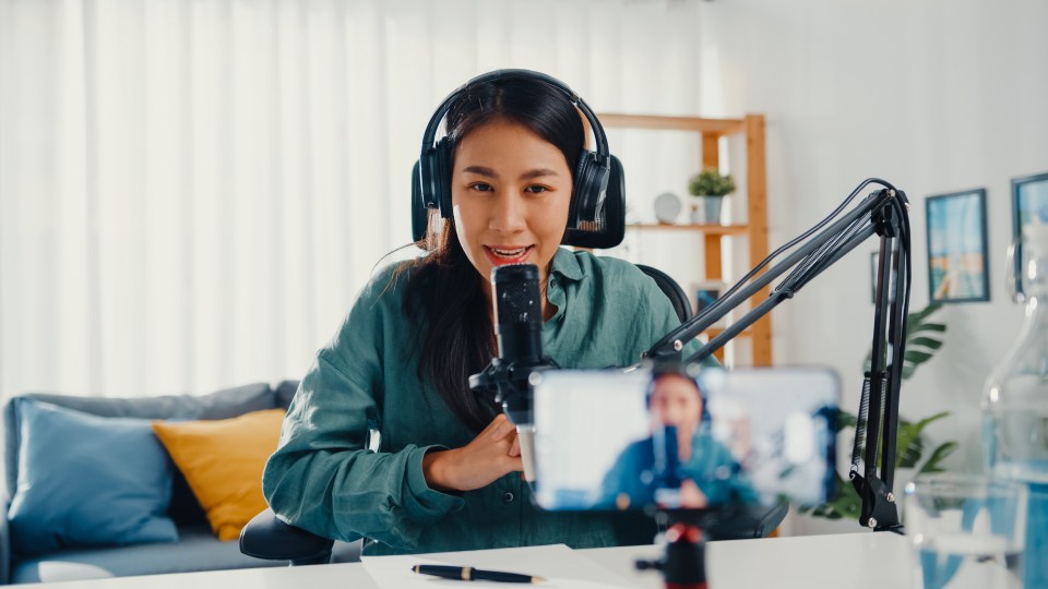 woman filming herself speaking into microphone and wearing headphones