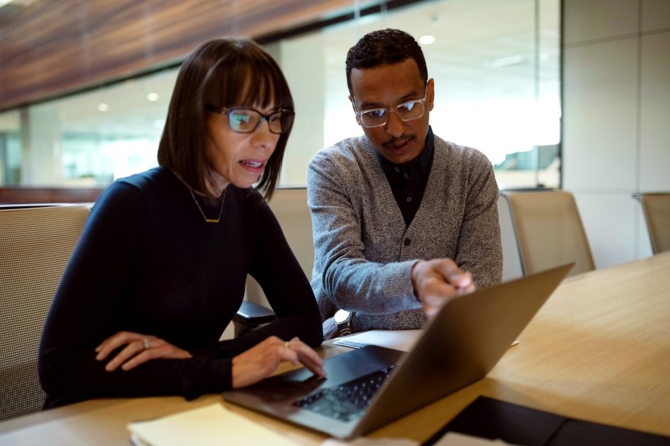 Two people looking a laptop in an office