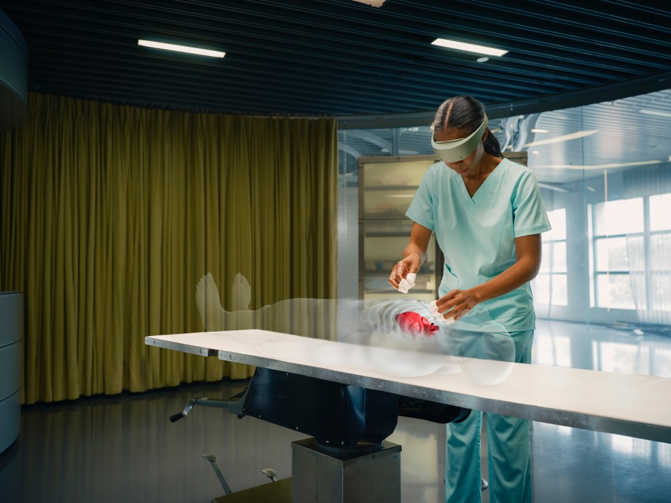 woman practices virtual surgery on operation table using Quest 2 headshet