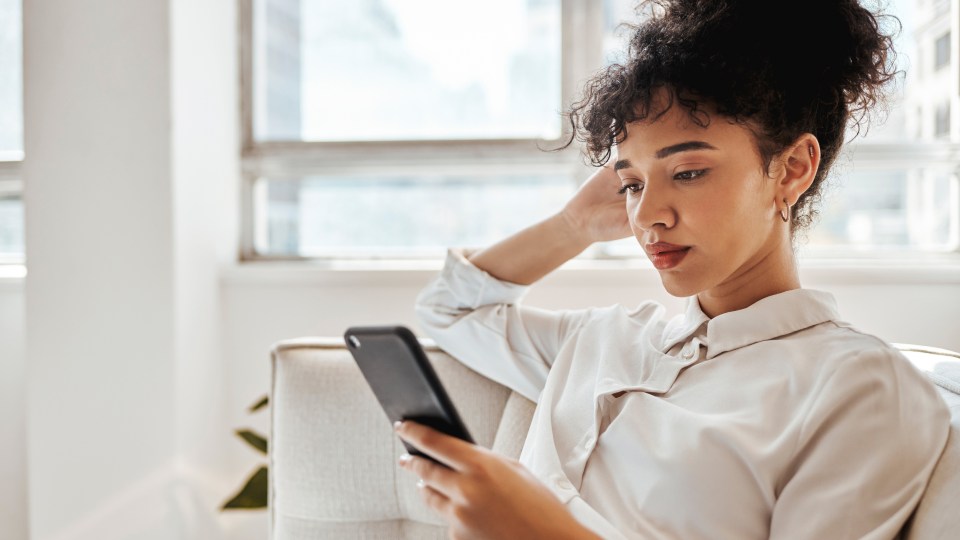 An image of a woman sitting down, looking at her phone.