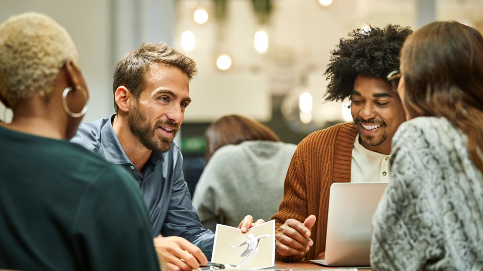 Photo of 4 people sitting around a table having a discussion