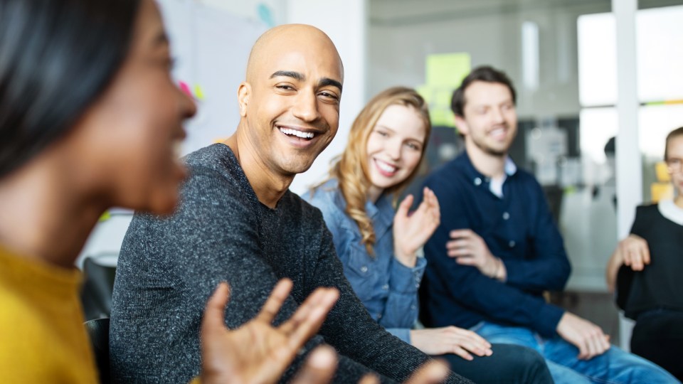 A group of smiling people having a discussion.