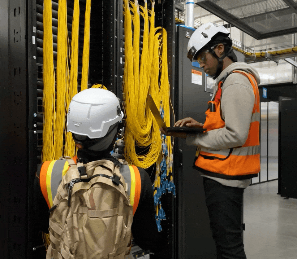 A GIF showing two fiber technicians working inside a data center.